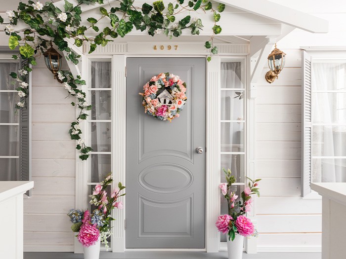 Porche d’entrée aux couleurs neutres décoré de verdure et de fleurs roses.
